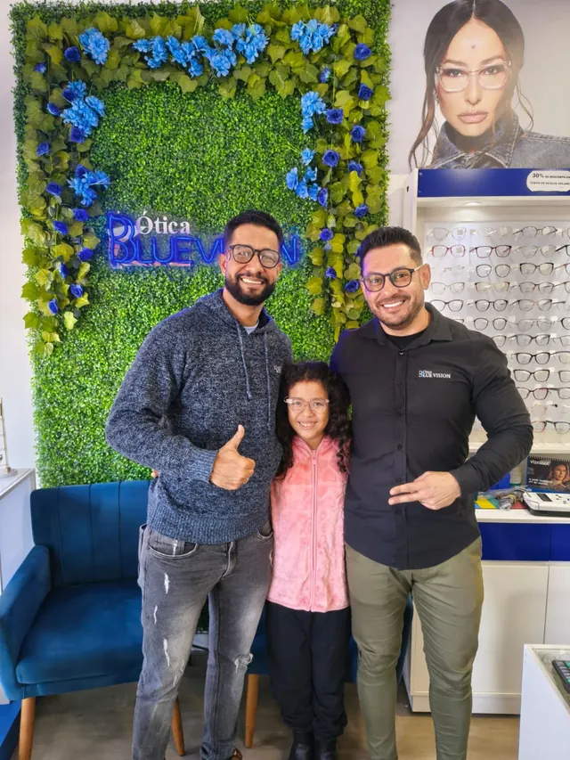 Pai, filha e um atendente da Blulens sorrindo juntos dentro da loja